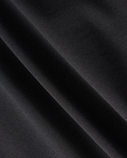 Close-up of a dark fabric with diagonal folds, showcasing a smooth texture and subtle sheen under light, reminiscent of the material in the Psycho Bunny MENS MAVERICK 10K PANT - B6P788D200. The fabric appears to be made of a fine, tightly woven material with impressive four-way stretch capabilities.