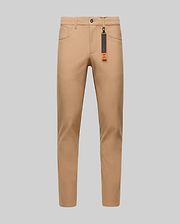 The Psycho Bunny MENS MAVERICK 10K STEP PANT - B6P788D200 is shown in slim-fit tan, featuring four-way stretch, front and back pockets, belt loops, and a black tag with an orange accent on the front belt loop against a gray background.