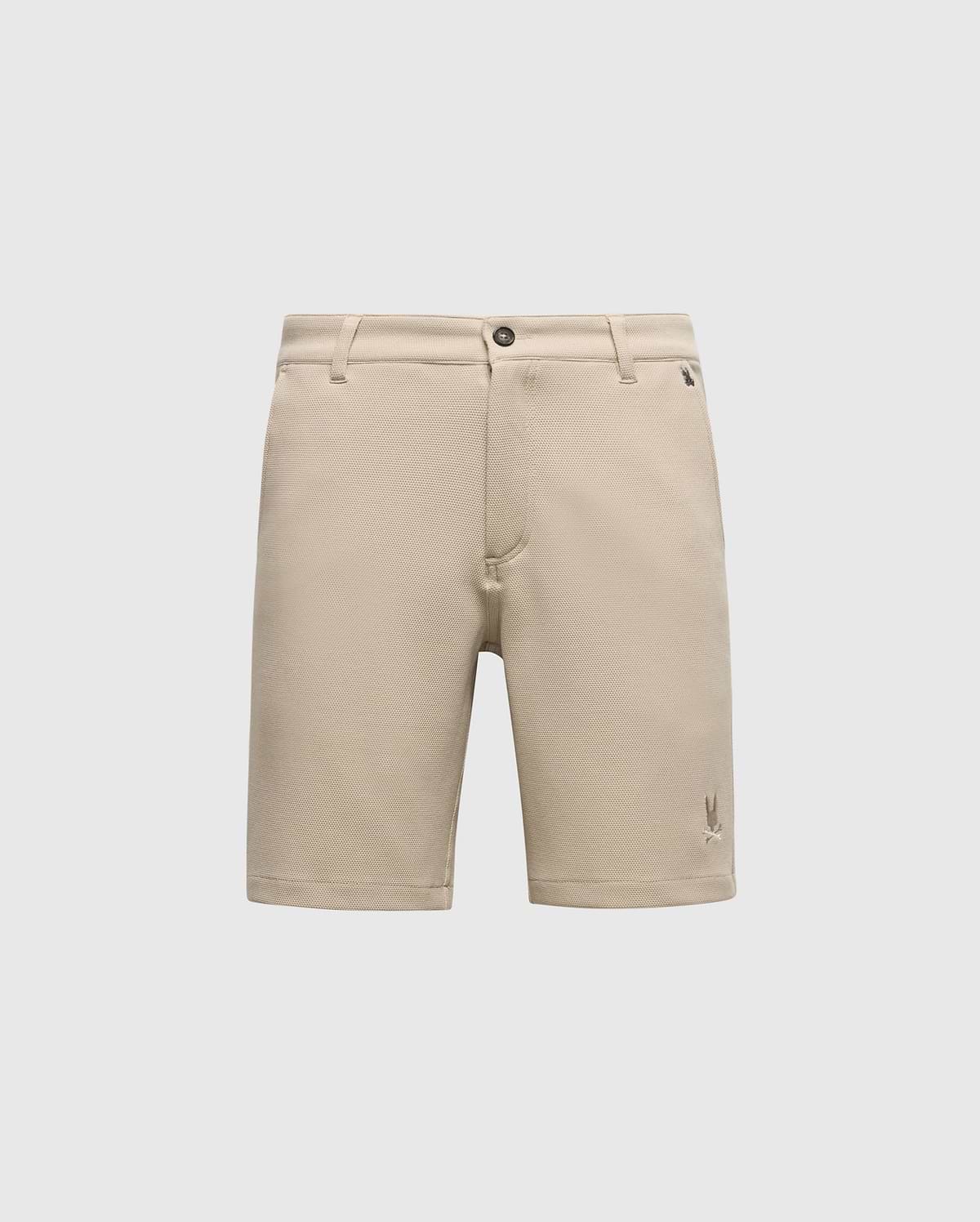 The Psycho Bunny MENS SHIRO KNIT HONEYCOMB SHORT (B6R585F200) is a beige, honeycomb-patterned piqué short with belt loops, front button and zipper closure, and a small embroidered logo near the left hem, shown on a white background.