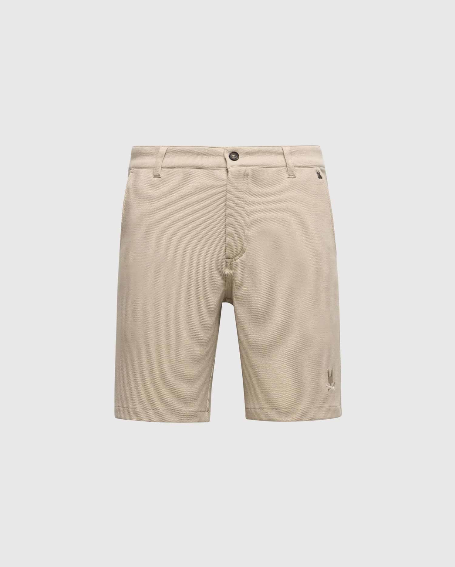 The Psycho Bunny MENS SHIRO KNIT HONEYCOMB SHORT (B6R585F200) is a beige, honeycomb-patterned piqué short with belt loops, front button and zipper closure, and a small embroidered logo near the left hem, shown on a white background.