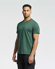 A man with short curly hair wears the Psycho Bunny MENS CLASSIC CREW NECK TEE (B6U014F200) in green, featuring a small embroidered chest logo, paired with black pants against a plain light background.