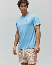 Mens Classic Crew Neck Tee in light blue premium jersey, featuring a classic fit and a small, multi-color embroidered Psycho Bunny skull logo on the left chest, paired with cream shorts featuring a colorful grid pattern and small bunny logos. (2)