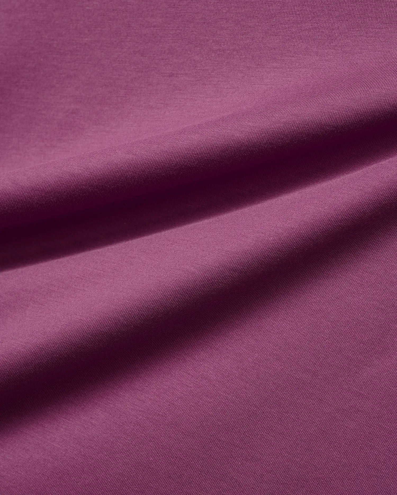 Mens Classic Crew Neck Tee in a luxurious, soft plum-colored jersey knit fabric, featuring subtle folds that highlight its smooth texture and rich, vibrant hue, embodying premium Psycho Bunny style.
