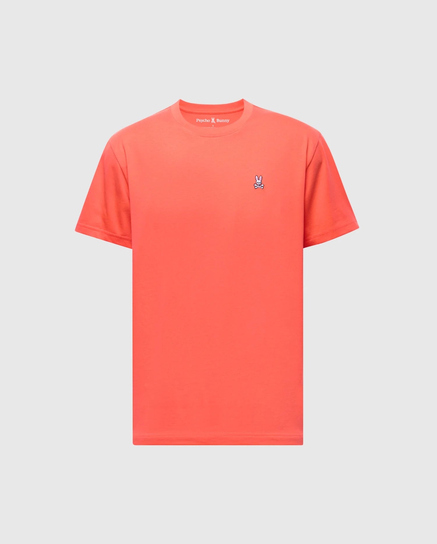 The men's classic crew neck tee (B6U014F200) by Psycho Bunny, made from soft Pima cotton, showcases a small embroidered bunny logo on its chest with a red-orange hue against a light gray backdrop.
