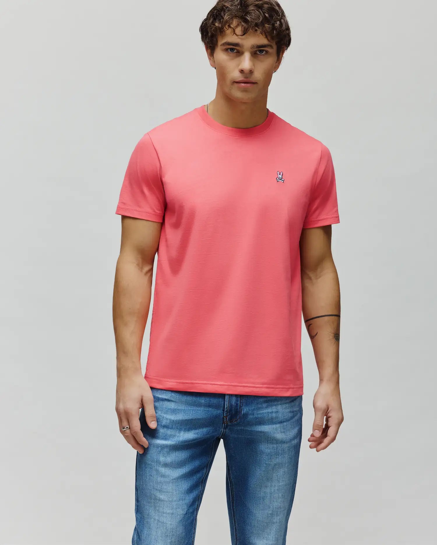 Mens Classic Crew Neck Tee in coral, featuring a classic fit and soft jersey knit fabric. Small embroidered Psycho Bunny skull logo on the left chest with white, black, and pink details. (4)