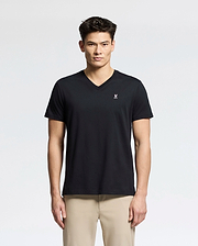 A person in a black Psycho Bunny MENS CLASSIC V NECK TEE - B6U100ARPC, made of soft Pima cotton with a small white logo on the chest, stands against a plain background. They have short dark hair and are dressed in beige pants.