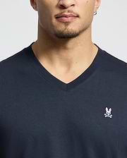 A person is wearing the MENS CLASSIC V NECK TEE by Psycho Bunny, made from soft Pima cotton. It features the iconic pink bunny with crossbones logo on the chest, emphasizing the stylish design of the dark shirt and upper torso.