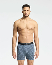A man with short curly hair stands against a plain white background, wearing Psycho Bunny's Mens 2 Pack Boxer Briefs (B6V481F200) featuring a black waistband. He looks directly at the camera, showcasing the comfort and style of the breathable stretch Pima cotton.