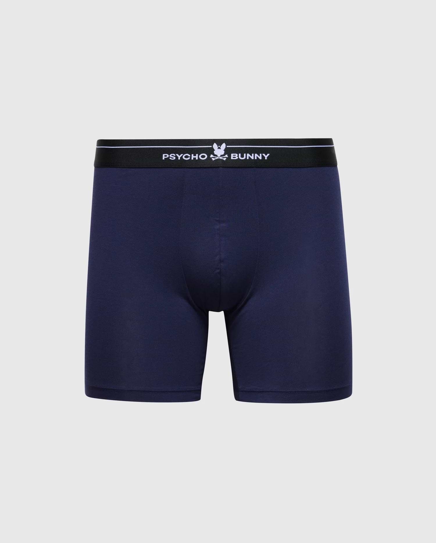 The Psycho Bunny Men's 2 Pack Boxer Briefs (B6V481F200) in navy blue are made from soft Pima cotton, featuring a black elastic waistband with "Psycho Bunny" and the bunny logo in white on a light gray background, offering stretchy knit comfort.