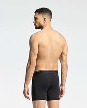 A man with short curly hair stands shirtless, facing away in Psycho Bunny MENS SOLID KNIT 2 PACK BOXER BRIEF (B6V906ARCM), black, against a plain light background.