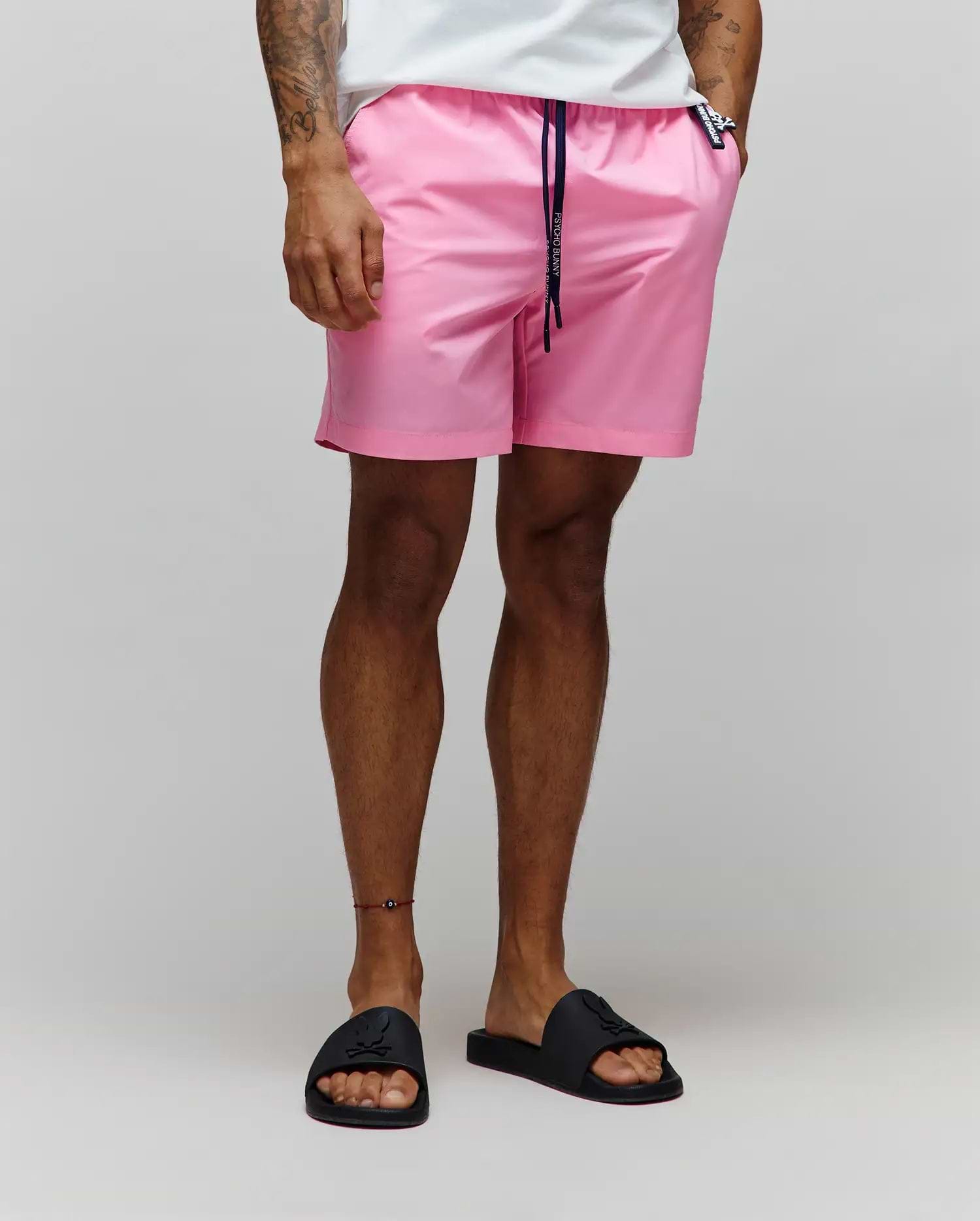Mens Samos Hydrochromic Printed Swim Trunk in vibrant pink, featuring a relaxed fit, smooth quick-dry fabric, navy drawstring with Psycho Bunny text, and a small black bunny skull logo tag on the right pocket.
