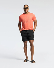 Coral jersey t-shirt with a large outline Psycho Bunny skull logo on the chest, paired with black Mens Samos Hydrochromic Printed Swim Trunk featuring a small white bunny logo on the left leg and Psycho Bunny drawstring.