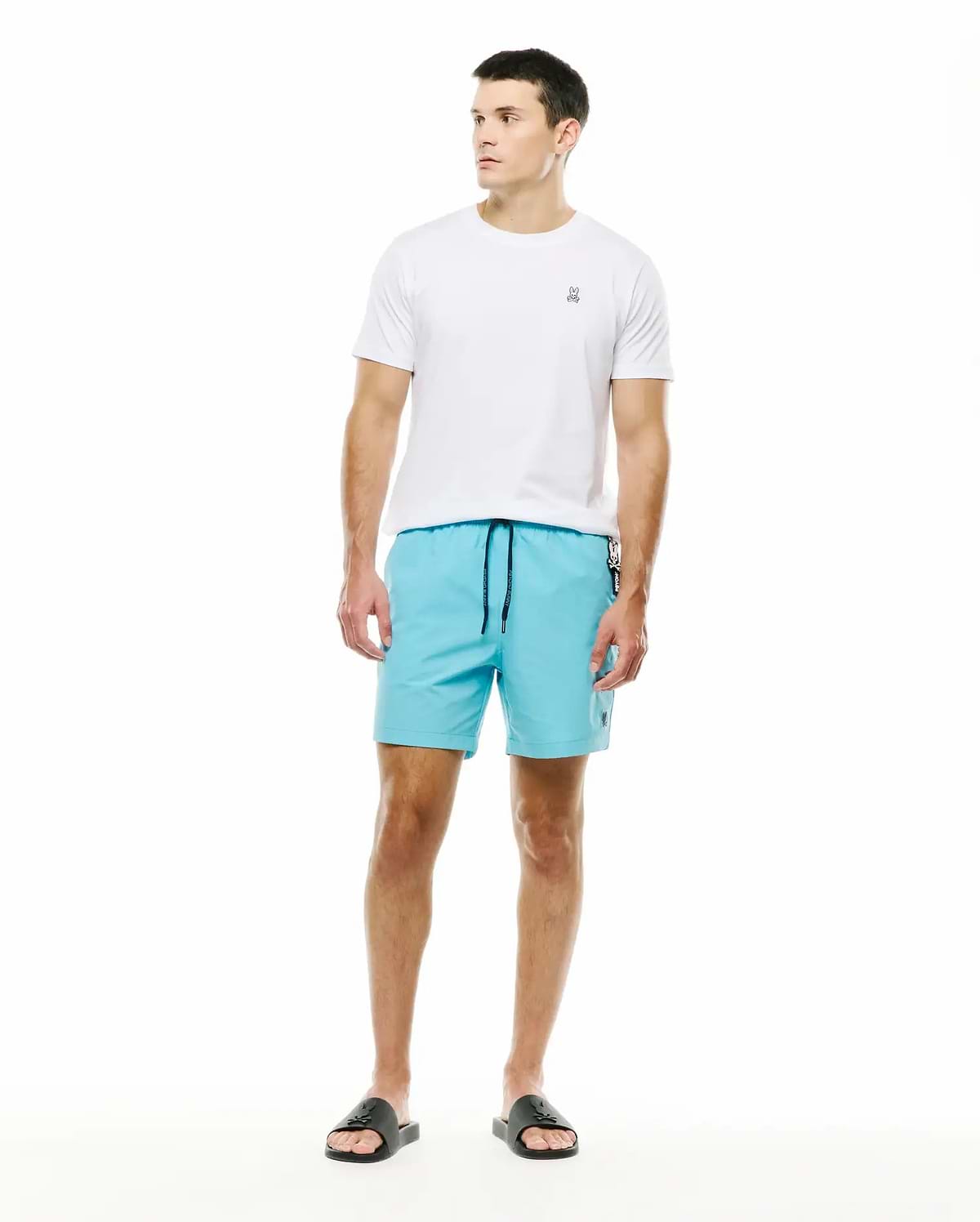 Mens Samos Hydrochromic Swim Trunks in aqua blue, featuring a black drawstring and small embroidered Psycho Bunny logo, complemented by a classic fit white jersey t-shirt with a small embroidered skull on the left chest. (5)