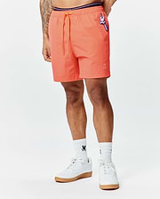 Mens Samos Hydrochromic Printed Swim Trunk in vibrant coral, relaxed fit, smooth fabric, orange drawstring, purple waistband, small embroidered bunny skull, and Psycho Bunny logo tag.