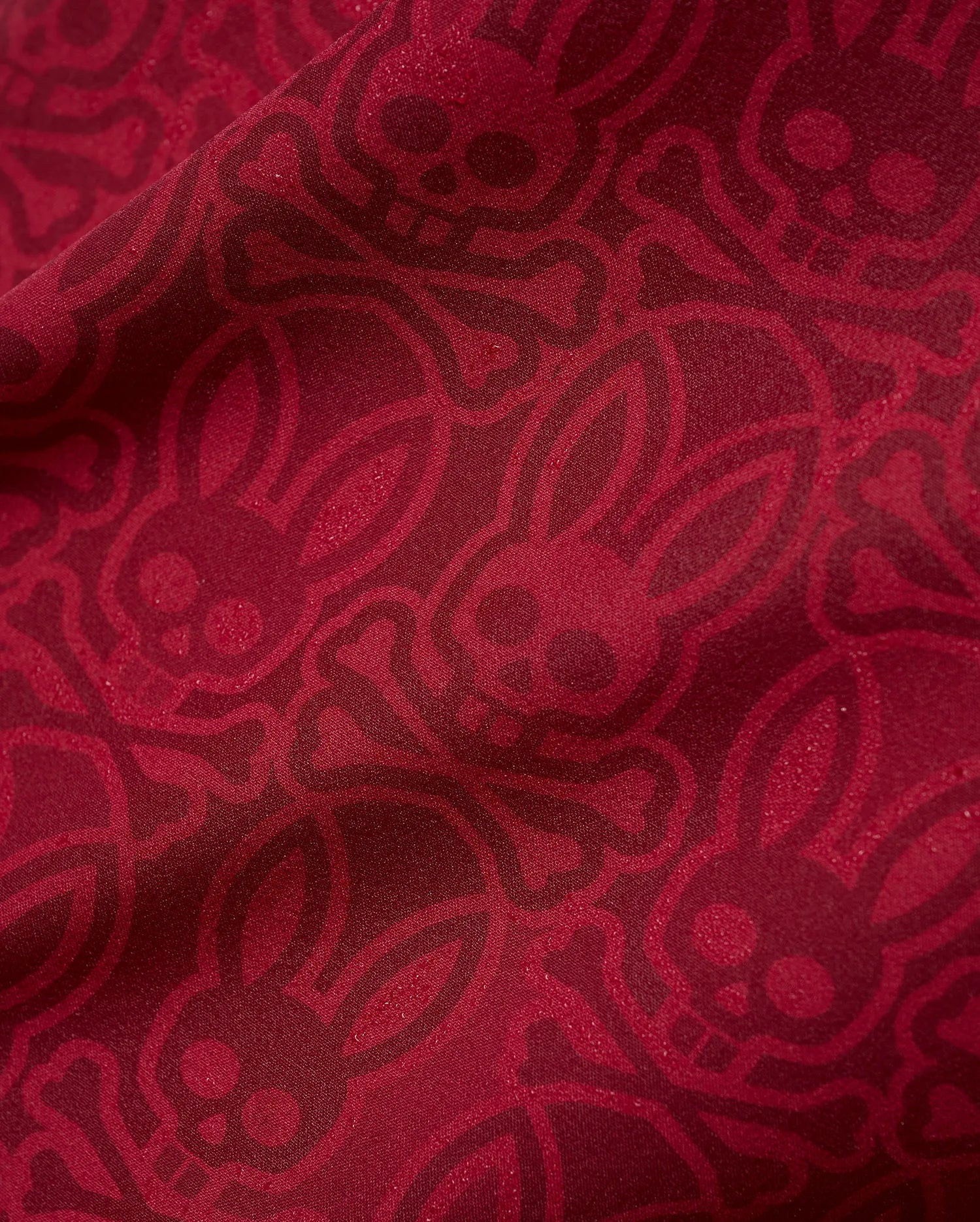 Mens Samos Hydrochromic Printed Swim Trunk in rich red, featuring an all-over darker red hydrochromic Psycho Bunny skull and crossbones pattern on smooth fabric. (7)