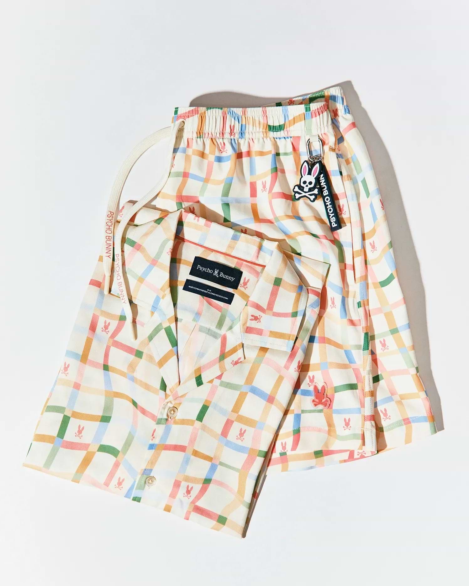 Mens Atlas Swim Trunk and matching short-sleeve shirt. Off-white vibrant plaid fabric with repeated small bunny skull logos, large embroidered bunny skull on shorts, Psycho Bunny drawstring, logo keychain.