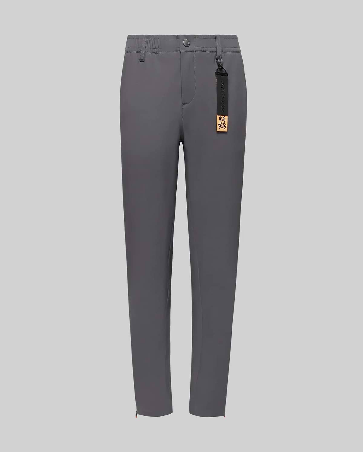 The Psycho Bunny KIDS MATHIEU COMMUTER PANT (KB0600002) features a classic fit, straight-leg gray style with front pockets, button and zipper closure, partial elastic waistband, and a black tag with gold label on the belt loop.