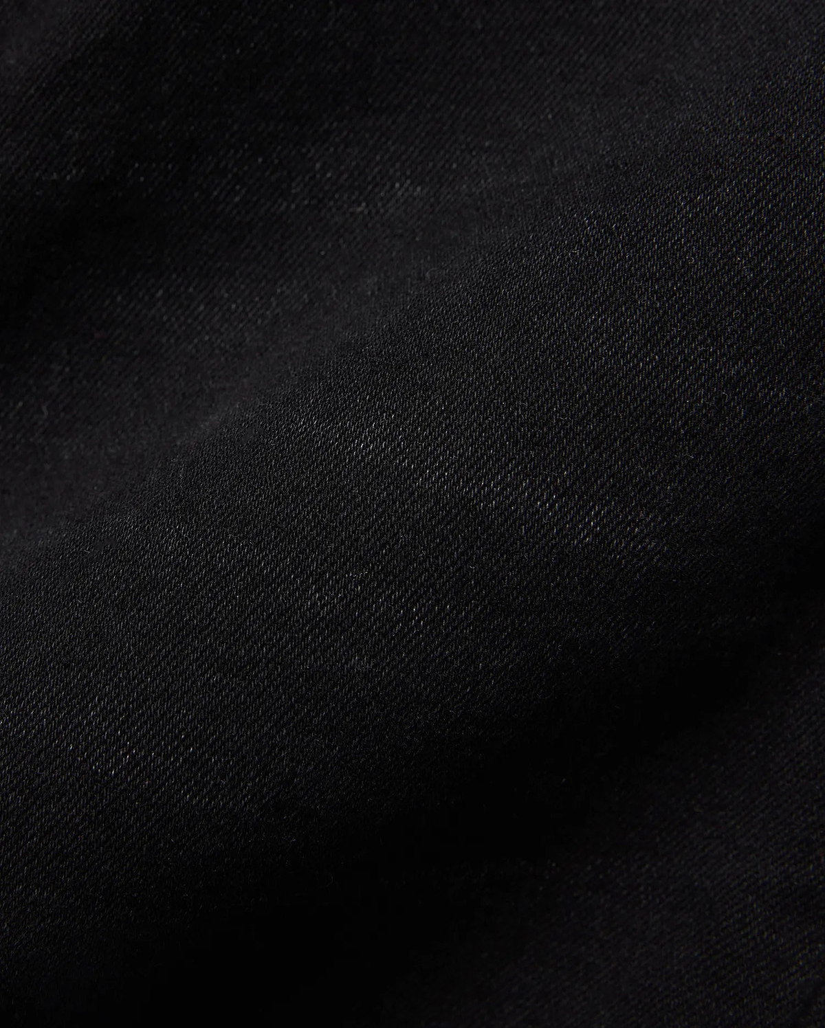 Kids Emerson Denim Pant, showcasing the rich, deep black denim fabric with a distinct diagonal twill weave texture. The premium quality material is subtly creased, highlighting its refined finish.