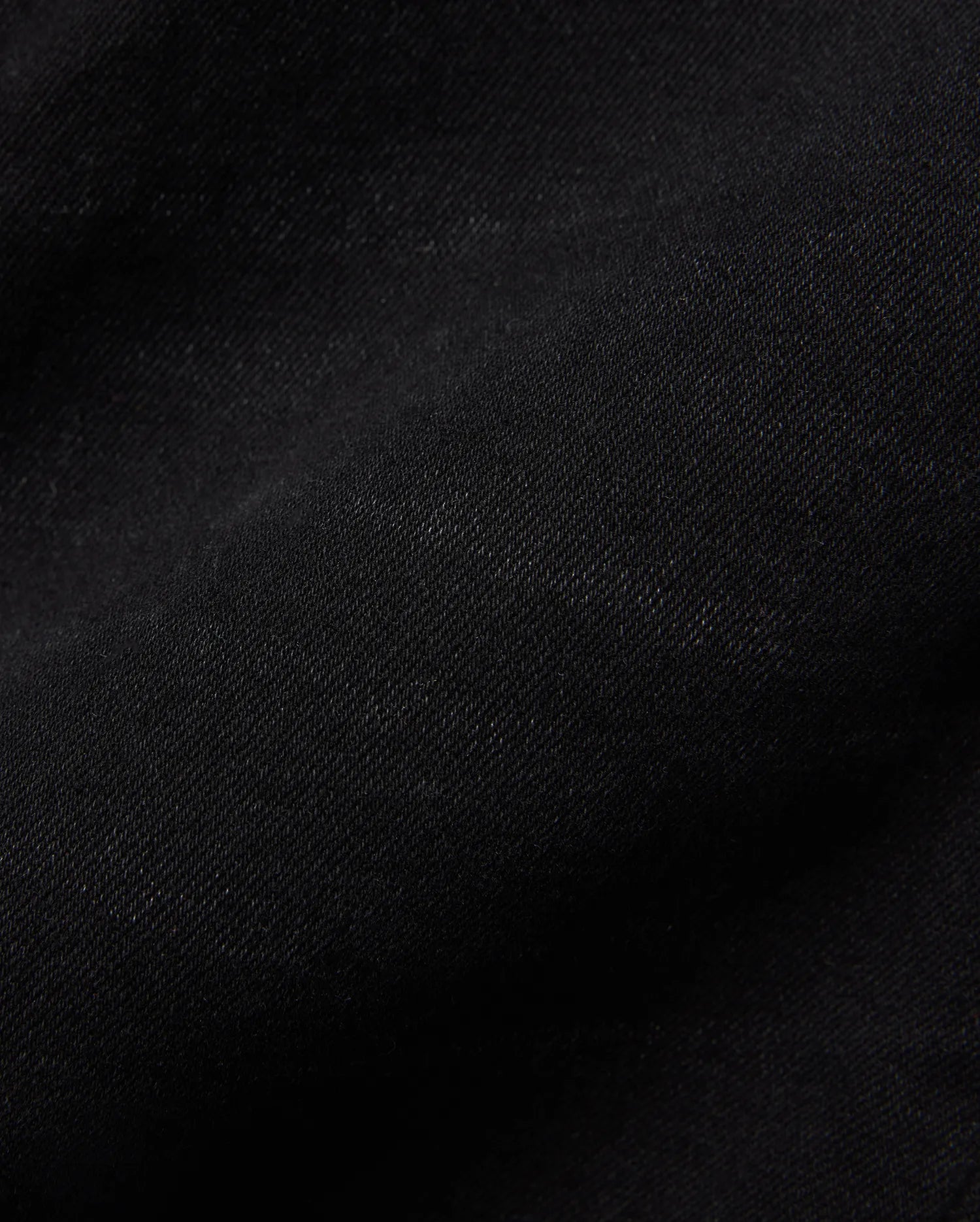 Kids Emerson Denim Pant, showcasing the rich, deep black denim fabric with a distinct diagonal twill weave texture. The premium quality material is subtly creased, highlighting its refined finish.