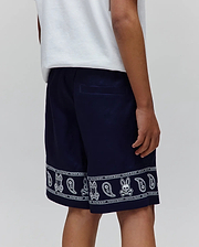 Kids Luke Tencel Short in navy, featuring a relaxed fit and a white bandana-style print along the hem with repeated Psycho Bunny text, skull logos, bunny skulls, and paisley patterns.