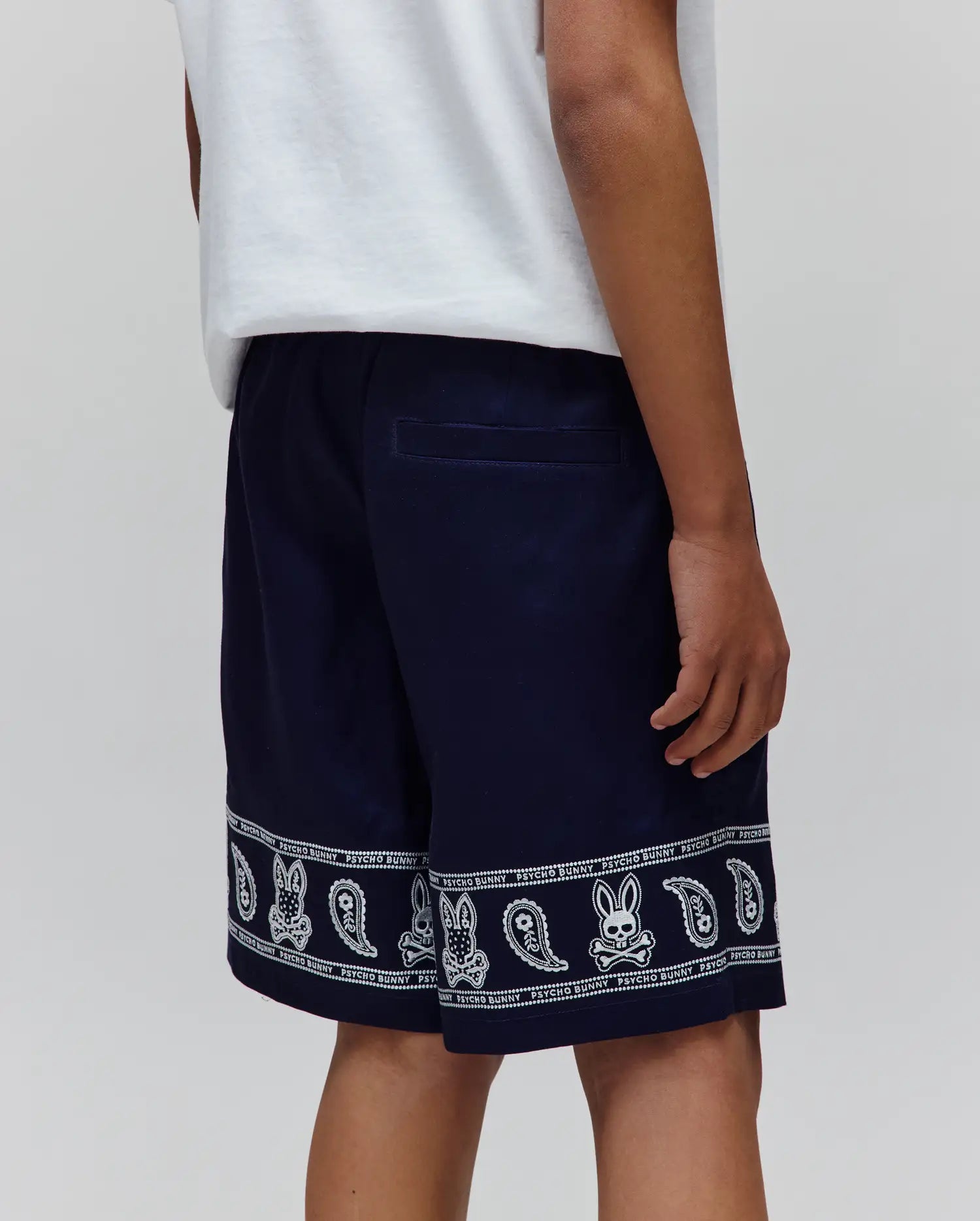Kids Luke Tencel Short in navy, featuring a relaxed fit and a white bandana-style print along the hem with repeated Psycho Bunny text, skull logos, bunny skulls, and paisley patterns.