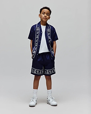 Navy relaxed fit short-sleeve shirt and Kids Luke Tencel Short set, both with a white border pattern of Psycho Bunny skull logos, paisley, and text along the shirt placket and short hem.