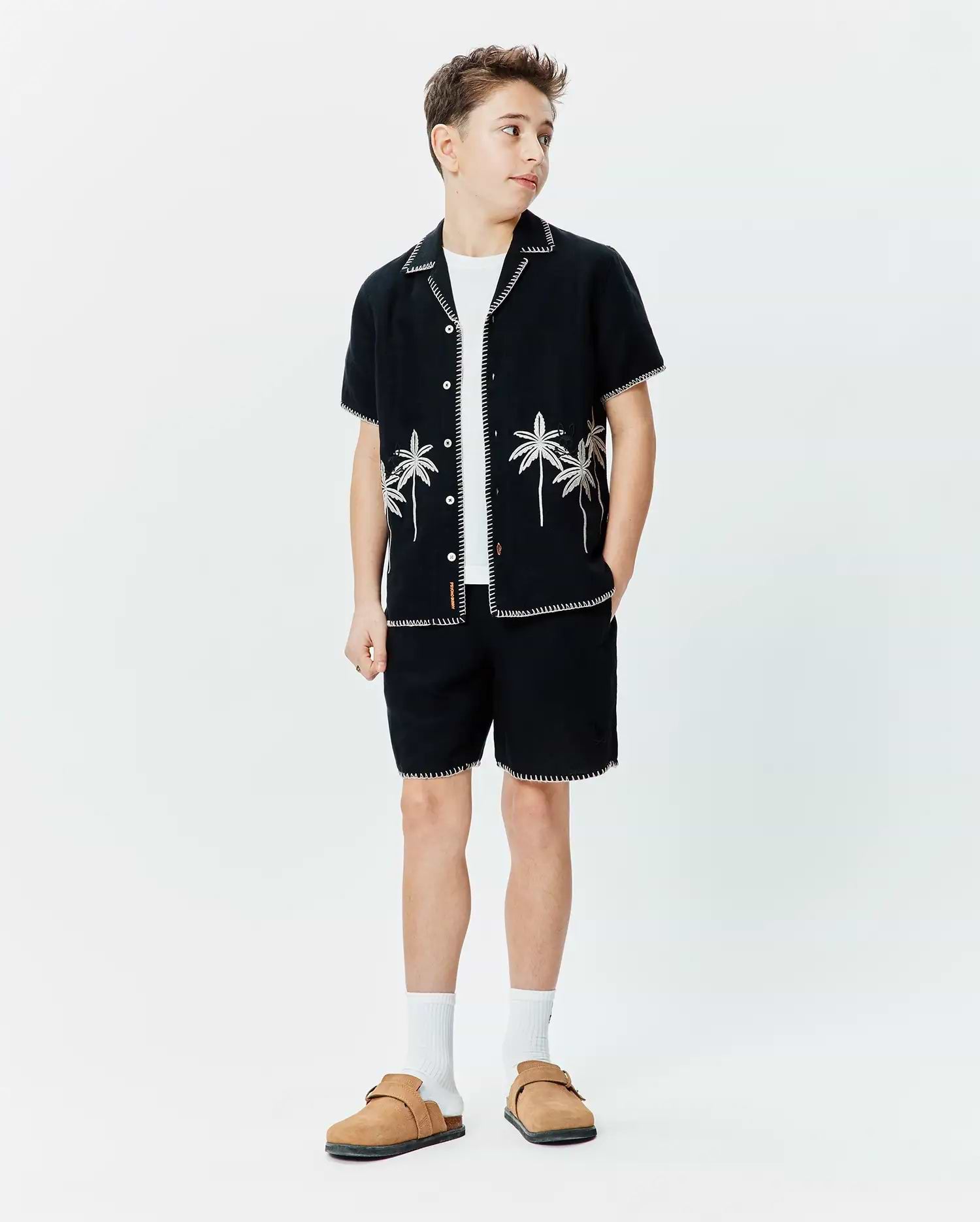 Black short-sleeve button-up shirt with white contrast stitching and palm tree embroidery, paired with matching Black Kids Brad Linen Short featuring white contrast stitching, both in a relaxed fit.