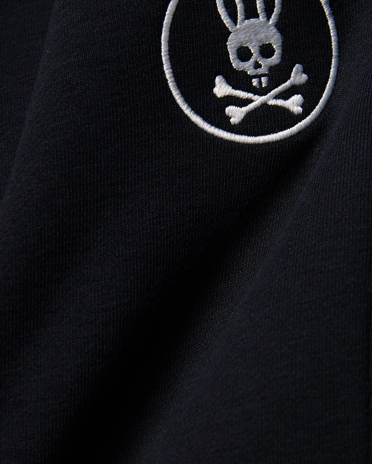Kids Nathaniel Sweatpant in deep navy blue, crafted from soft jersey knit fabric, featuring a prominent white embroidered Psycho Bunny skull and crossbones logo.