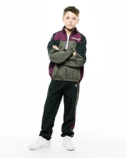 KIDS ALDER NYLON COLORBLOCK PANT in dark green/black with plum side stripe, featuring a small embroidered white Psycho Bunny skull logo on the left thigh. Relaxed fit crinkled nylon, part of a matching colorblock tracksuit. (1)