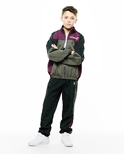 KIDS ALDER NYLON COLORBLOCK PANT in dark green/black with plum side stripe, featuring a small embroidered white Psycho Bunny skull logo on the left thigh. Relaxed fit crinkled nylon, part of a matching colorblock tracksuit. (1)