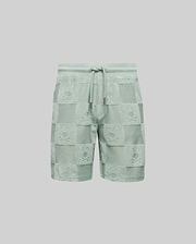 The Psycho Bunny KIDS KELVIN TOWEL TERRY SWEATSHORT (KB0900002) features light green cotton-blend jacquard terry, with a drawstring waist and a checkered pattern of alternating solid/textured squares and playful bunny heads.
