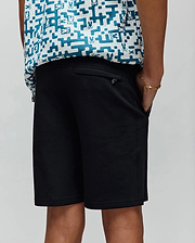Kids Barry Modal Short in black, featuring a relaxed fit, smooth modal fabric, side pockets, and a small metallic Psycho Bunny logo tag on the rear pocket.