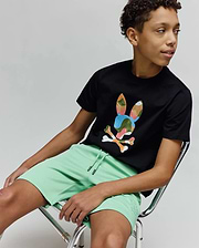 Black jersey t-shirt with a large, colorful abstract camo Psycho Bunny skull logo on the chest, paired with Kids Barry Modal Short in mint green featuring a tonal embroidered bunny logo on the leg and drawstring waist. (4)