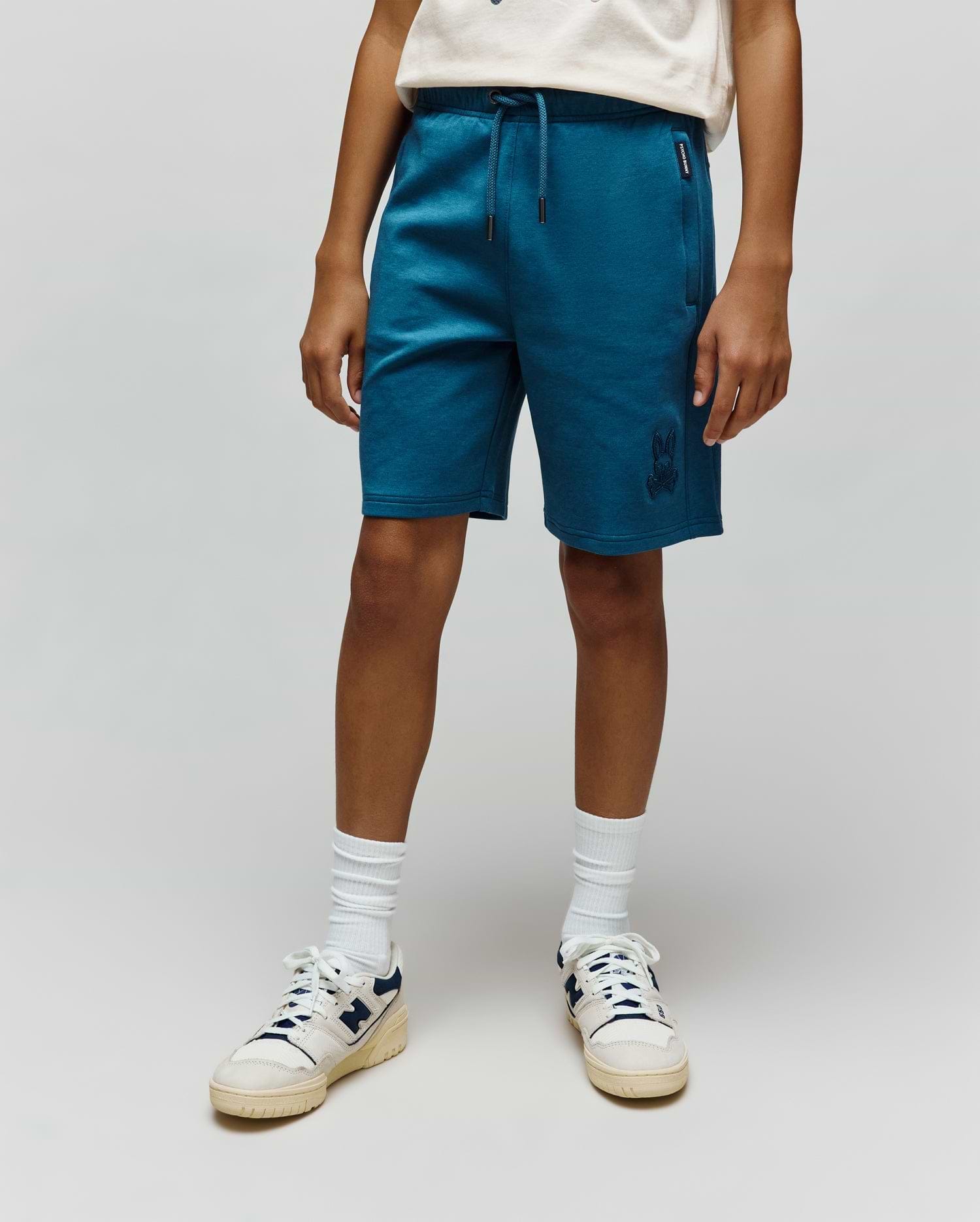 Kids Barry Modal Short in deep teal, featuring a relaxed fit, soft modal blend fabric, drawstring waist, and an embroidered Psycho Bunny skull logo on the lower left leg, with a woven brand tag on the left pocket.