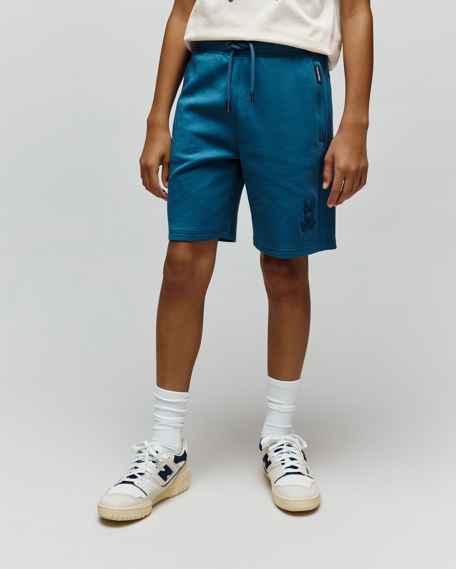 Kids Barry Modal Short in deep teal, featuring a relaxed fit, soft modal blend fabric, drawstring waist, and an embroidered Psycho Bunny skull logo on the lower left leg, with a woven brand tag on the left pocket.
