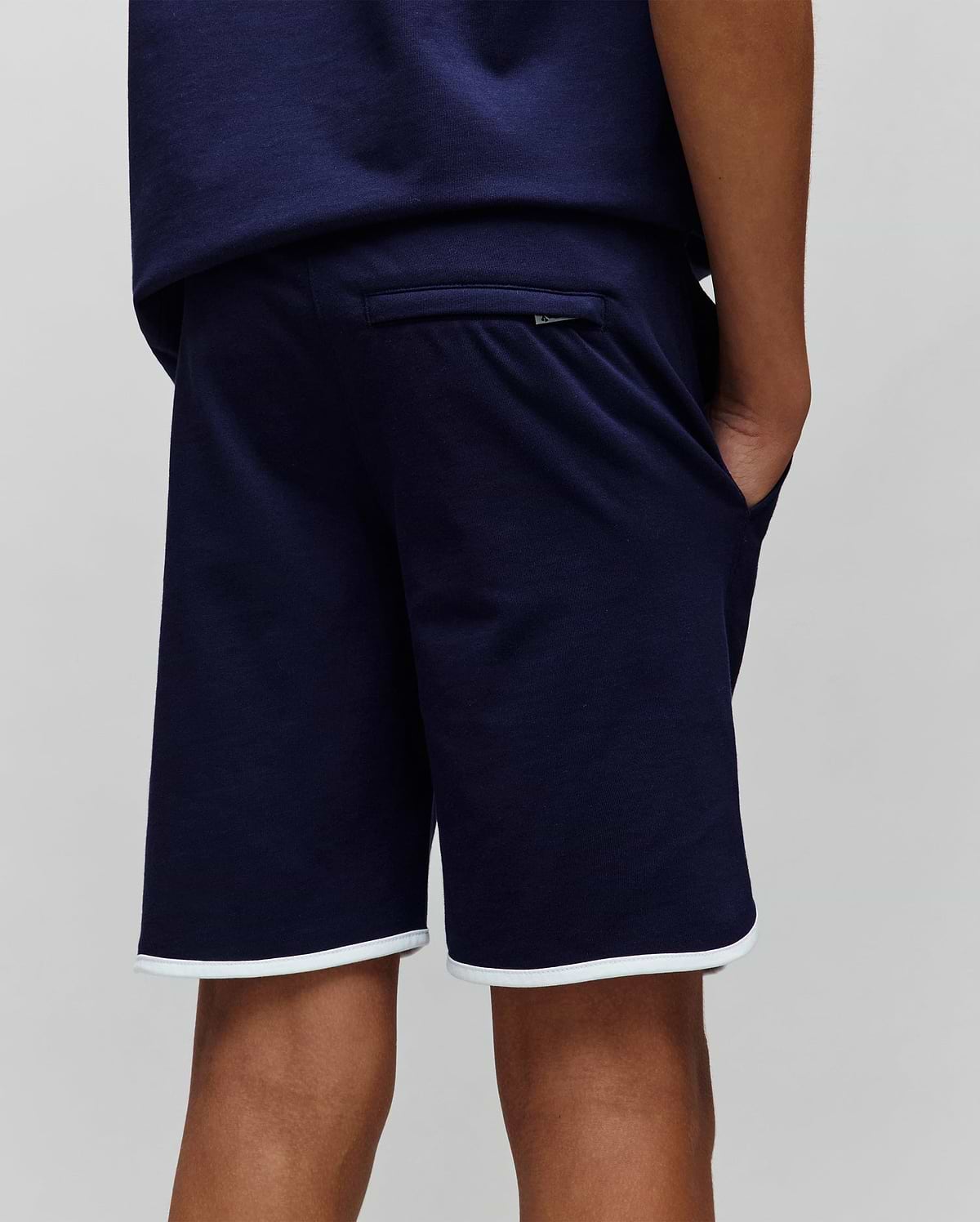 Deep navy blue Kids Toby Short, a relaxed fit in soft jersey fabric, featuring crisp white contrast piping on the hem and a small Psycho Bunny logo tag on the back welt pocket.
