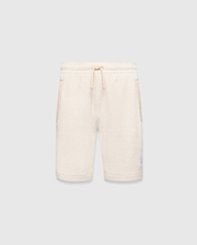 Kids Keith Short, cream textured knit with relaxed fit, featuring a matching drawstring waist, side pockets with cream trim, and a small light blue embroidered Psycho Bunny skull logo on the lower left leg.