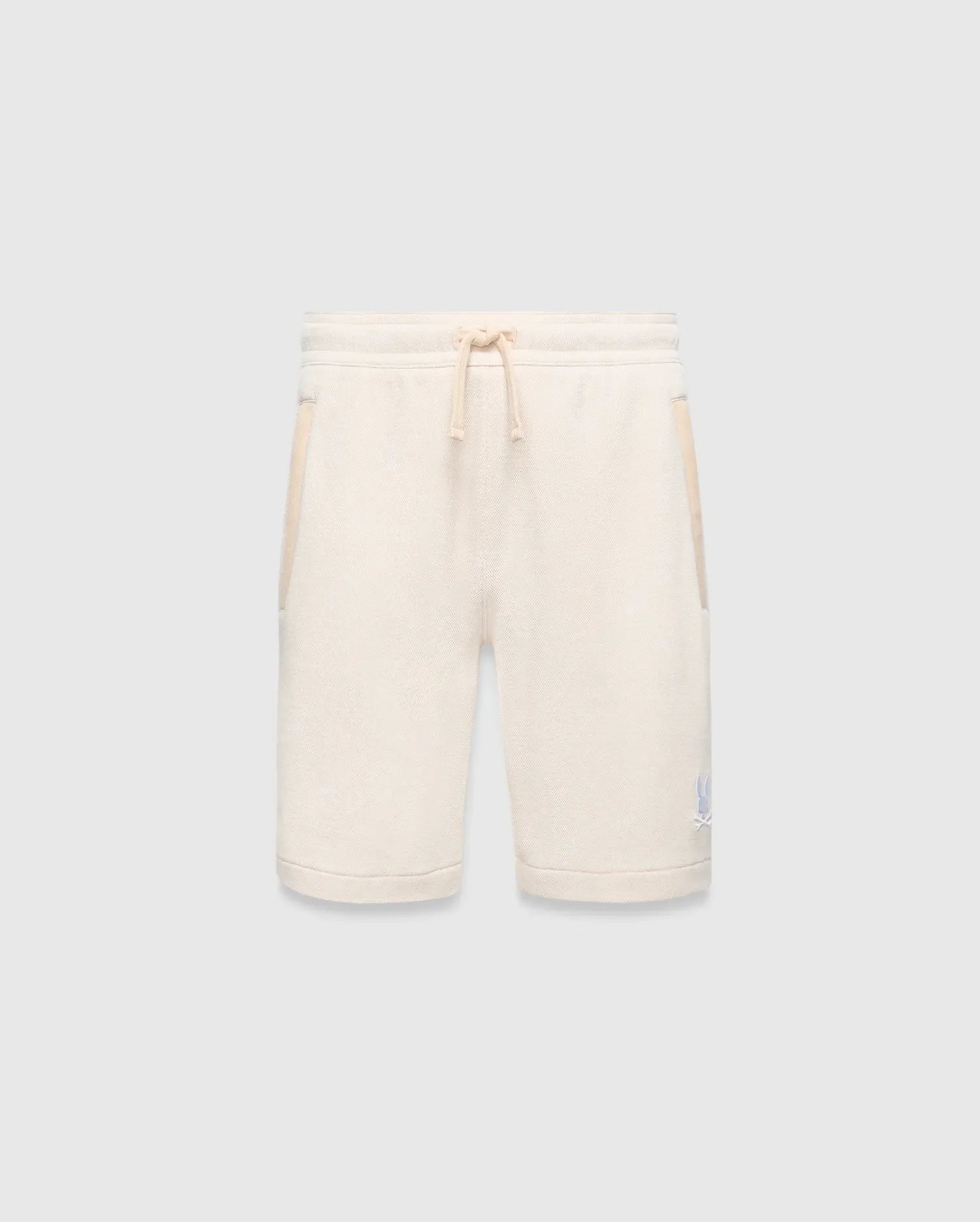 Kids Keith Short, cream textured knit with relaxed fit, featuring a matching drawstring waist, side pockets with cream trim, and a small light blue embroidered Psycho Bunny skull logo on the lower left leg.