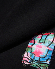Kids Isaac Print Short in black jersey, featuring a large, vibrant Psycho Bunny skull logo with pink, blue, green, and white paint-splatter print and a raised black outline.