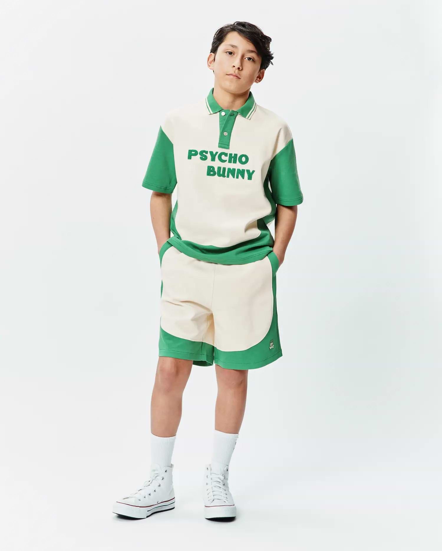 Premium Psycho Bunny cream and green color block polo shirt with bold chest text, paired with matching soft knit Kids Kelly Short featuring a subtle embroidered bunny skull logo.
