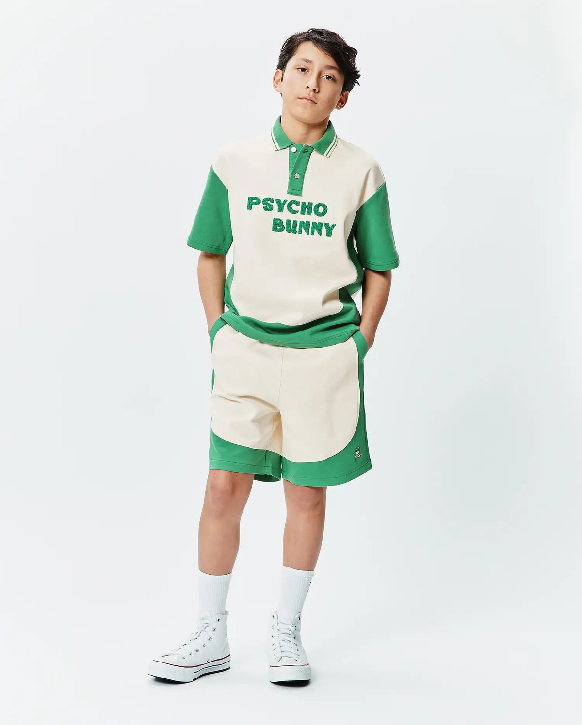 Premium Psycho Bunny cream and green color block polo shirt with bold chest text, paired with matching soft knit Kids Kelly Short featuring a subtle embroidered bunny skull logo.