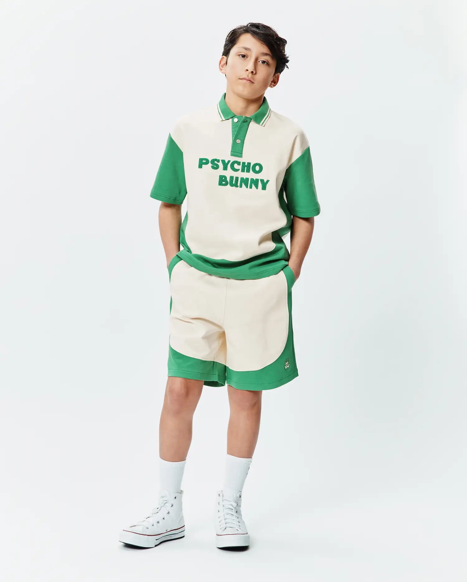 Premium Psycho Bunny cream and green color block polo shirt with bold chest text, paired with matching soft knit Kids Kelly Short featuring a subtle embroidered bunny skull logo.