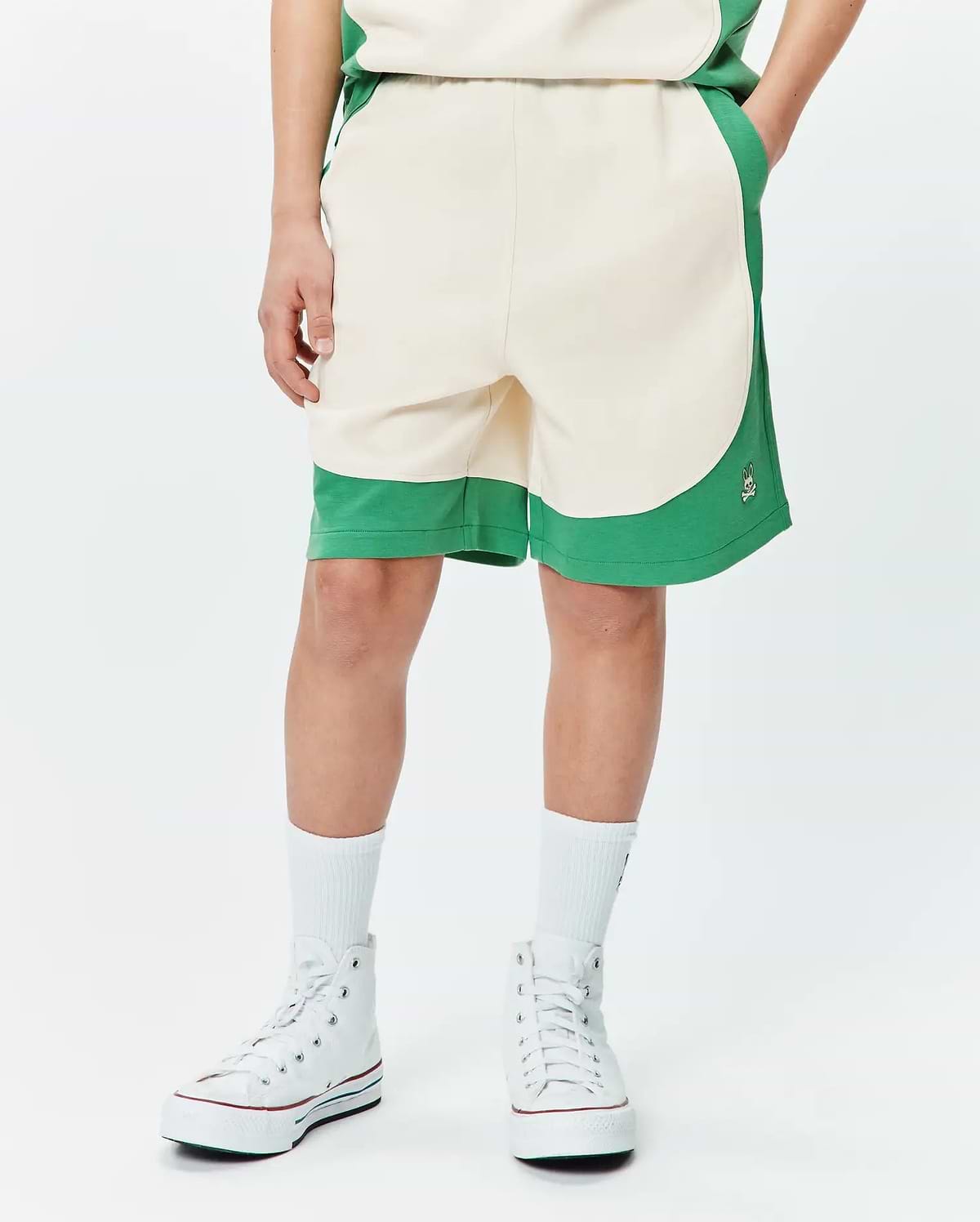 Kids Kelly Short, a relaxed fit cream and green color block short with a curved design, soft jersey fabric, and a small embroidered Psycho Bunny skull logo on the right leg.