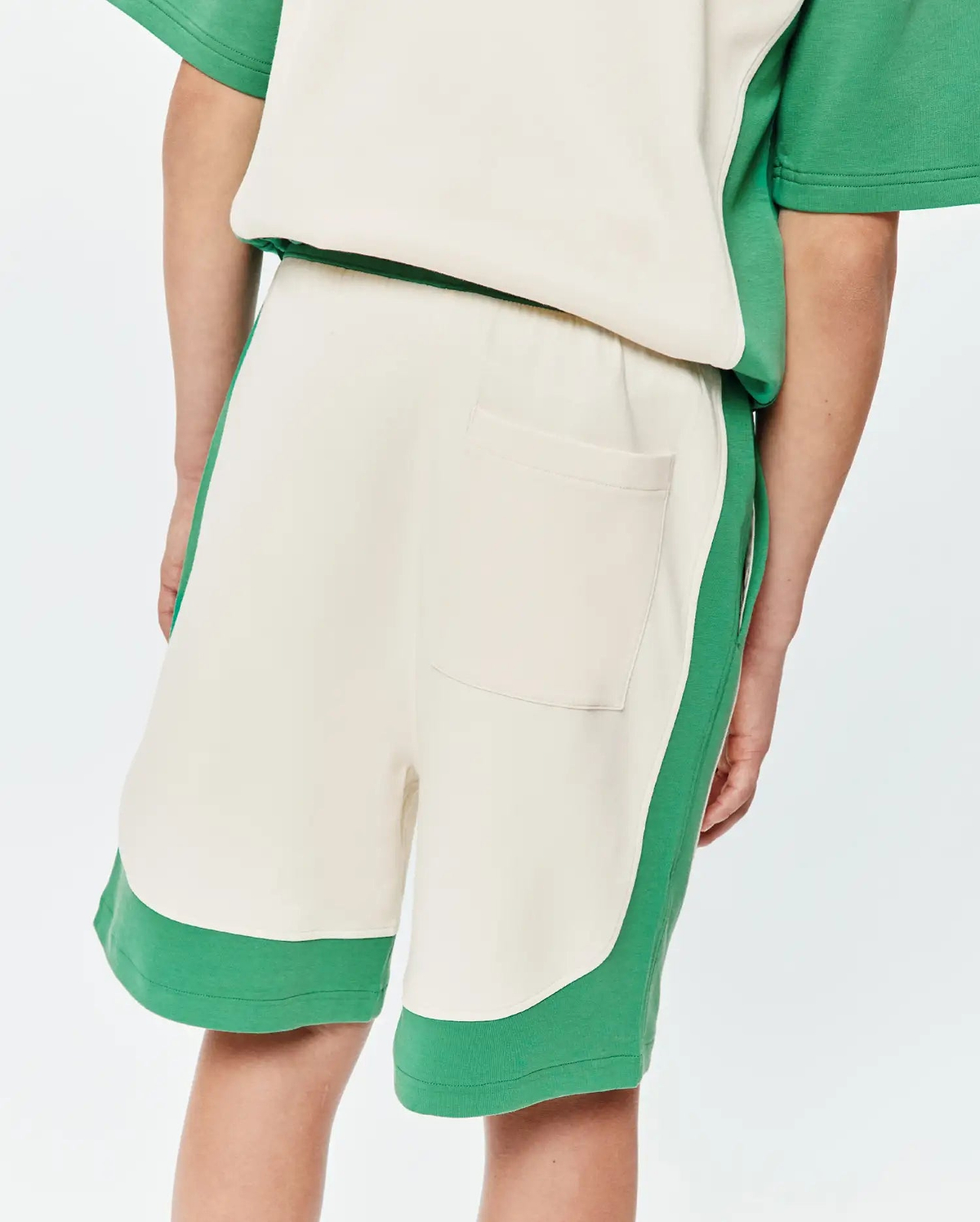 Kids Kelly Short, a relaxed fit, cream and green color-block design in soft french terry fabric, featuring curved green side panels, a green hem, and a single back patch pocket.