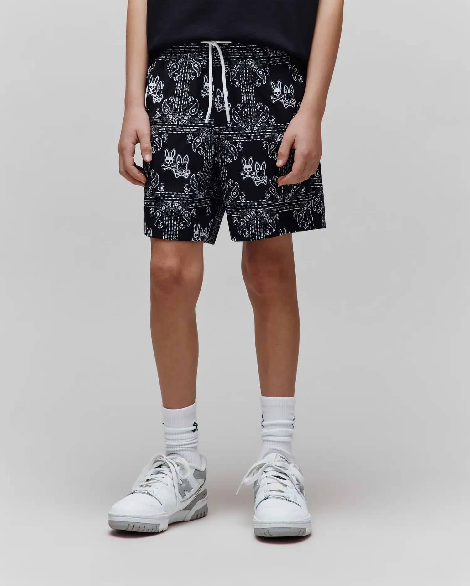 Kids Luke Swim Trunk, black with white all-over bandana print featuring repeated Psycho Bunny skull logos, relaxed fit, smooth fabric, and white drawstring.