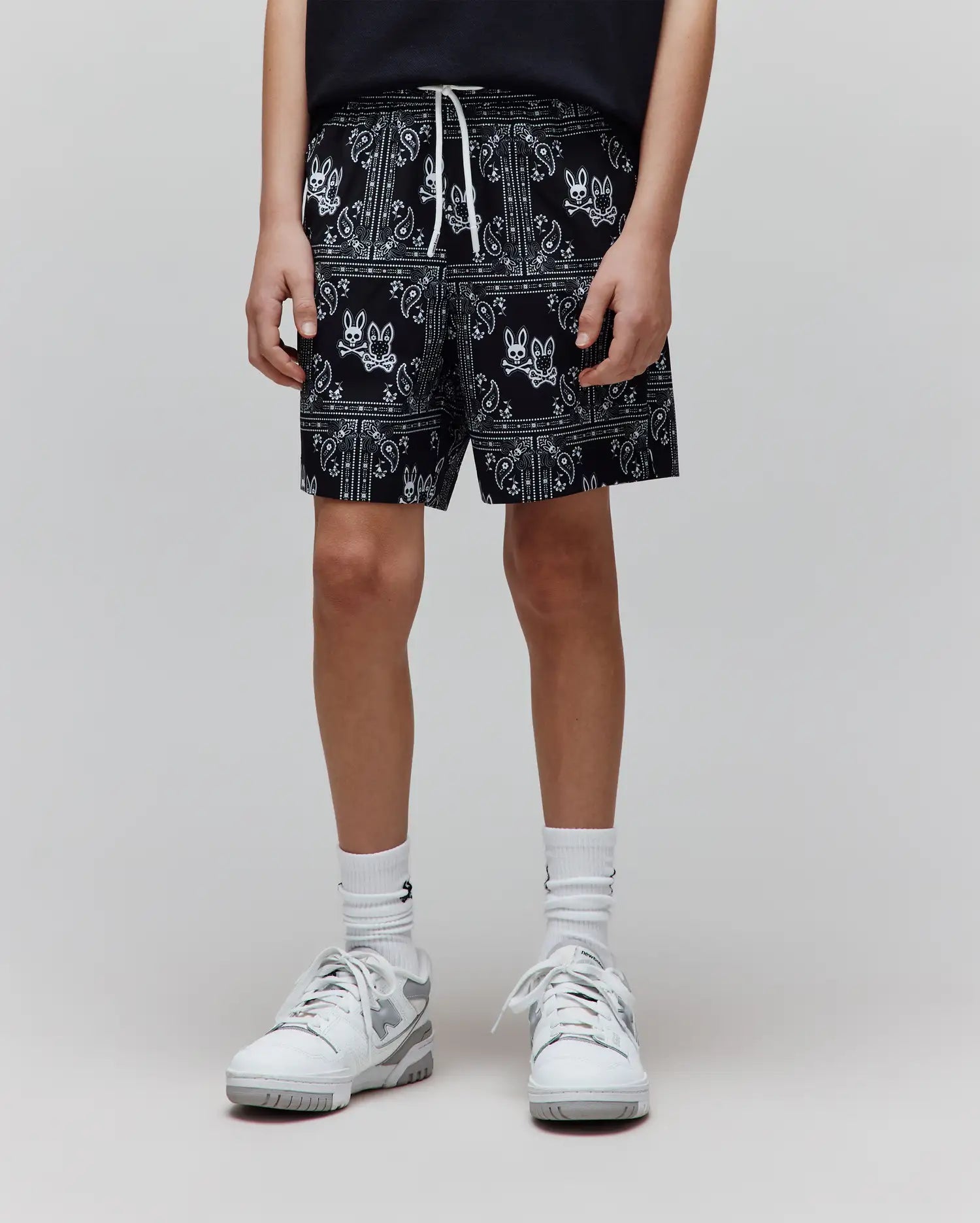 Kids Luke Swim Trunk, black with white all-over bandana print featuring repeated Psycho Bunny skull logos, relaxed fit, smooth fabric, and white drawstring.
