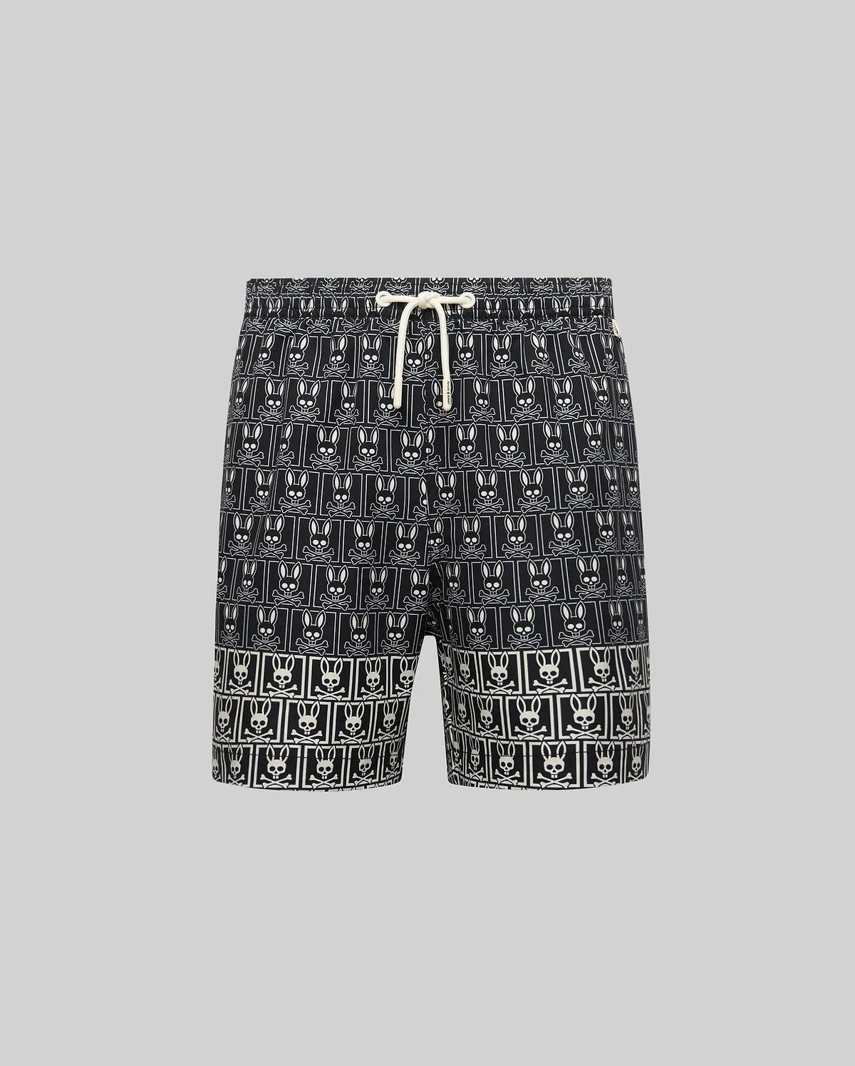 Kids Keon Swim Trunk in black, featuring a relaxed fit and a bold all-over white Psycho Bunny skull and crossbones logo pattern with a contrasting white drawstring.