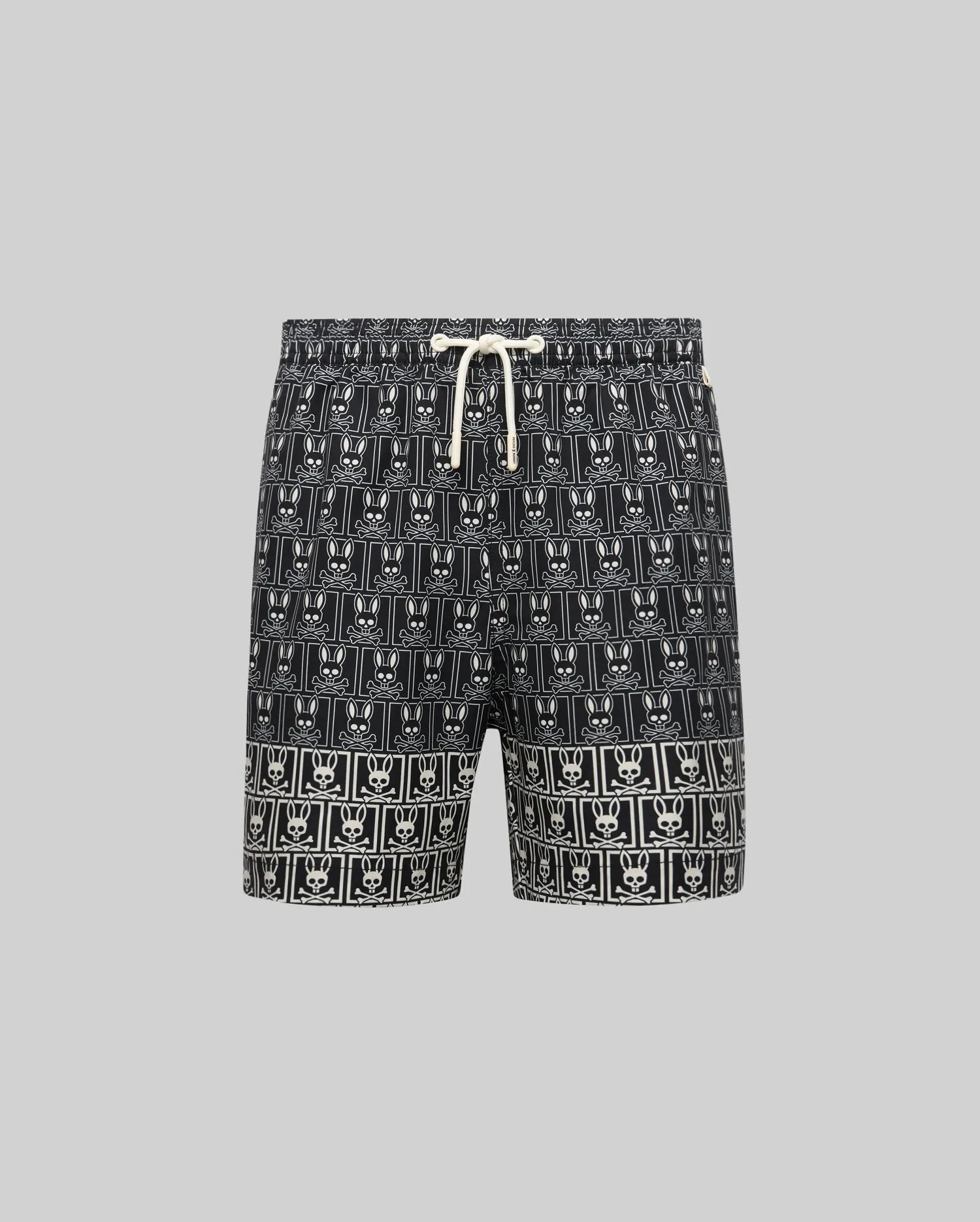 Kids Keon Swim Trunk in black, featuring a relaxed fit and a bold all-over white Psycho Bunny skull and crossbones logo pattern with a contrasting white drawstring.