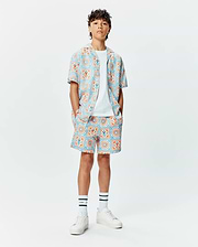 Kids Frank Swim Trunk and matching short-sleeve shirt, relaxed fit, with a vibrant light blue and orange geometric tile pattern featuring integrated small Psycho Bunny skull logos.