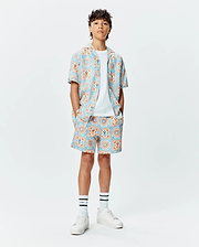 Kids Frank Swim Trunk and matching short-sleeve shirt, relaxed fit, with a vibrant light blue and orange geometric tile pattern featuring integrated small Psycho Bunny skull logos.